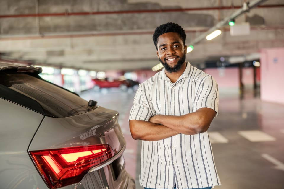 Man in a parking lot standing next to a vehicle