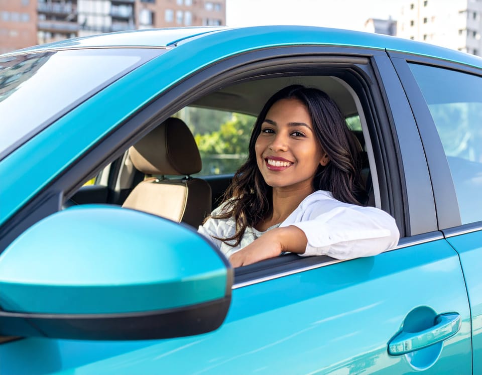 Woman driving a car, looking happy.