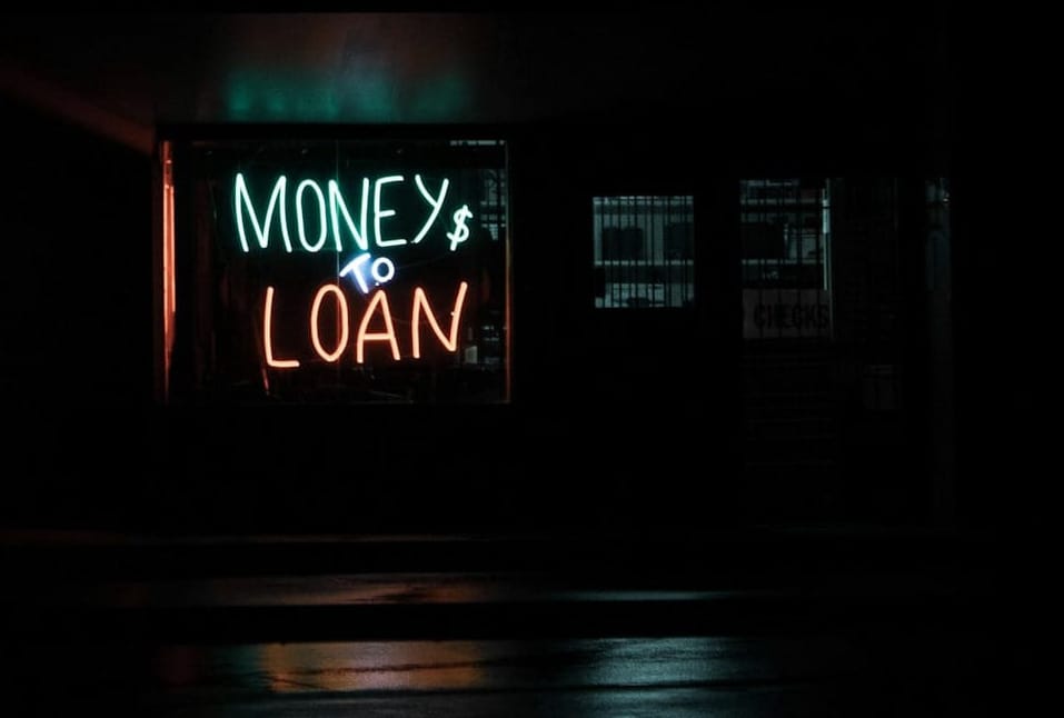 Photo of a storefront sign that says "Money to Loan" at night.